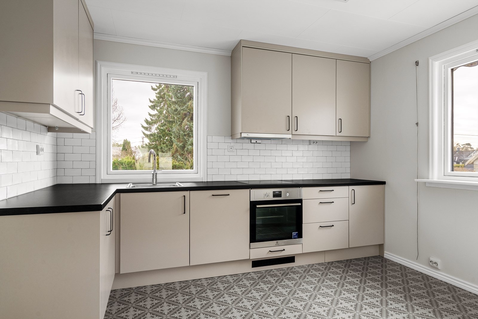 Lyst og innbydende kjøkken med god benkeplass og store vinduer som slipper inn rikelig med dagslys. Galleribilde