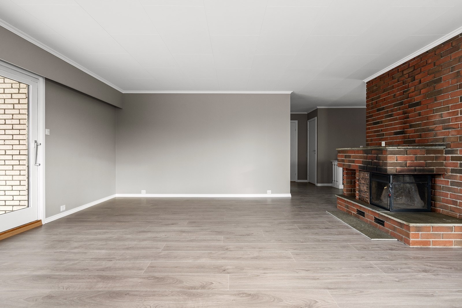 Romslig og innbydende stue med nylagte laminatgulv og murt teglsteinvegg med peis som gir rommet karakter. Galleribilde