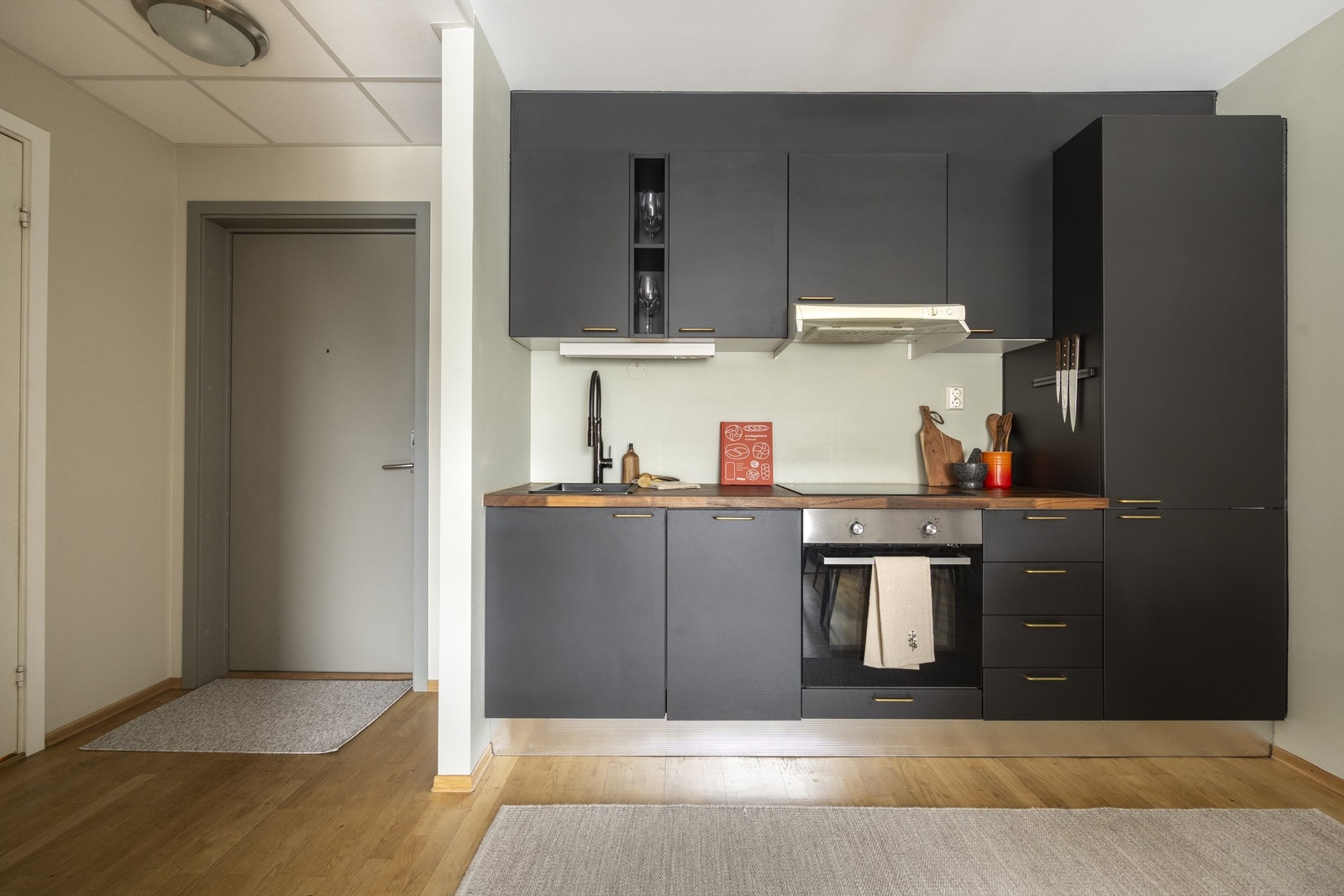 Kjøkkeninnredningen er tidløs med mørke, glatte fronter. Av integrerte hvitevarer er det platetopp, stekeovn, oppvaskmaskin og kjøl/-fryseskap. Galleribilde