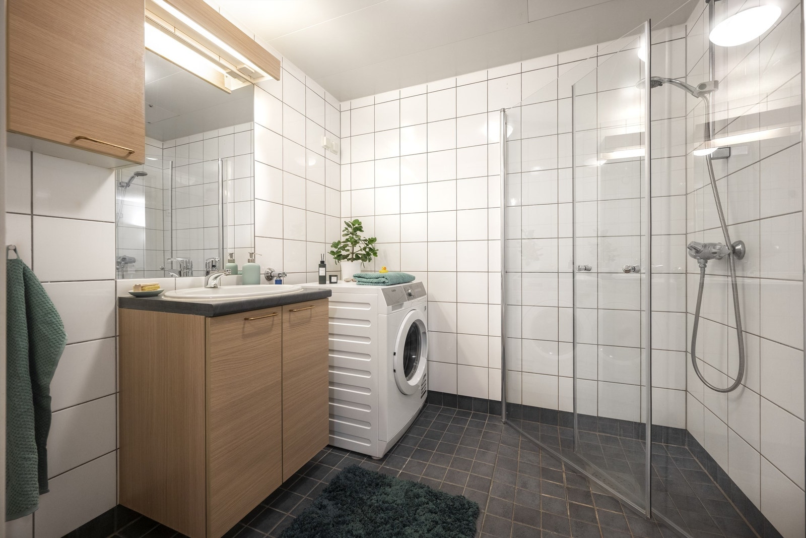 Badet er innredet med vegghengt toalett, innredning med nedfelt servant, speil m/lys og dusjhjørne med skyvbare glassdører. Det er opplegg for vaskemaskin. Galleribilde