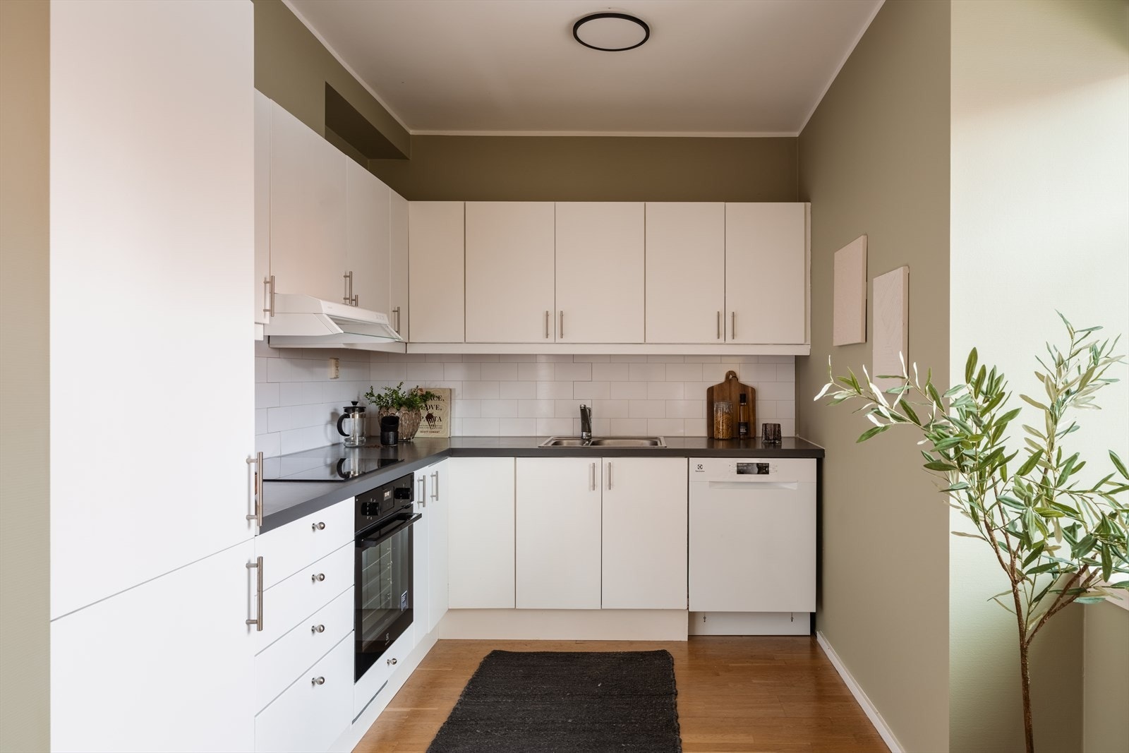 Moderne kjøkken med hvit innredning, grå laminatbenkeplate og integrerte hvitevarer fra 2026. Galleribilde