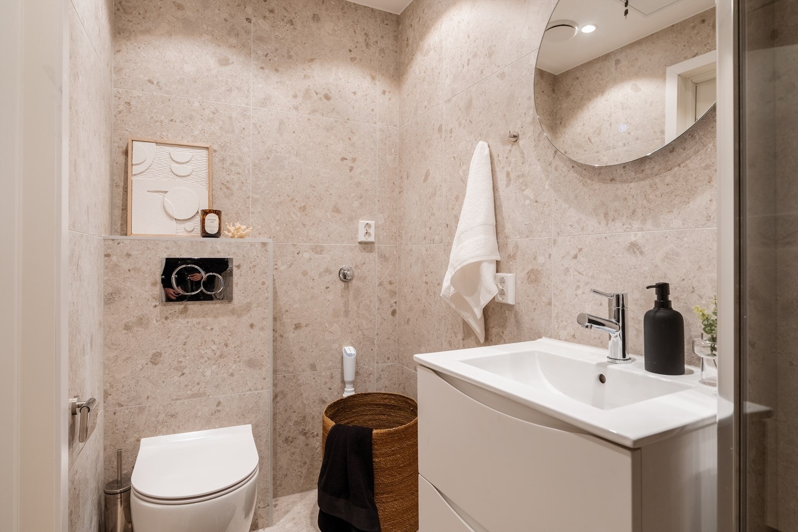 Badet har en stilren servant med møbel, speil og opplegg for vaskemaskin. Galleribilde