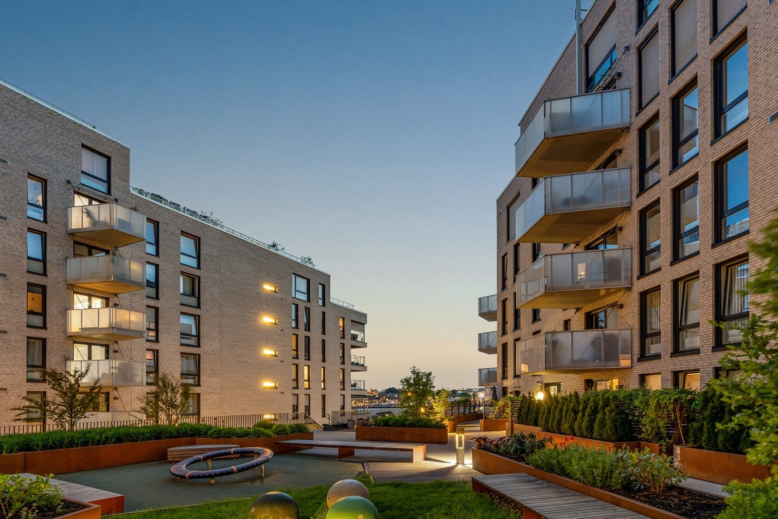 Pent indre gårdsrom med beplantning, lekeapparater, sittebenker m.m. Galleribilde