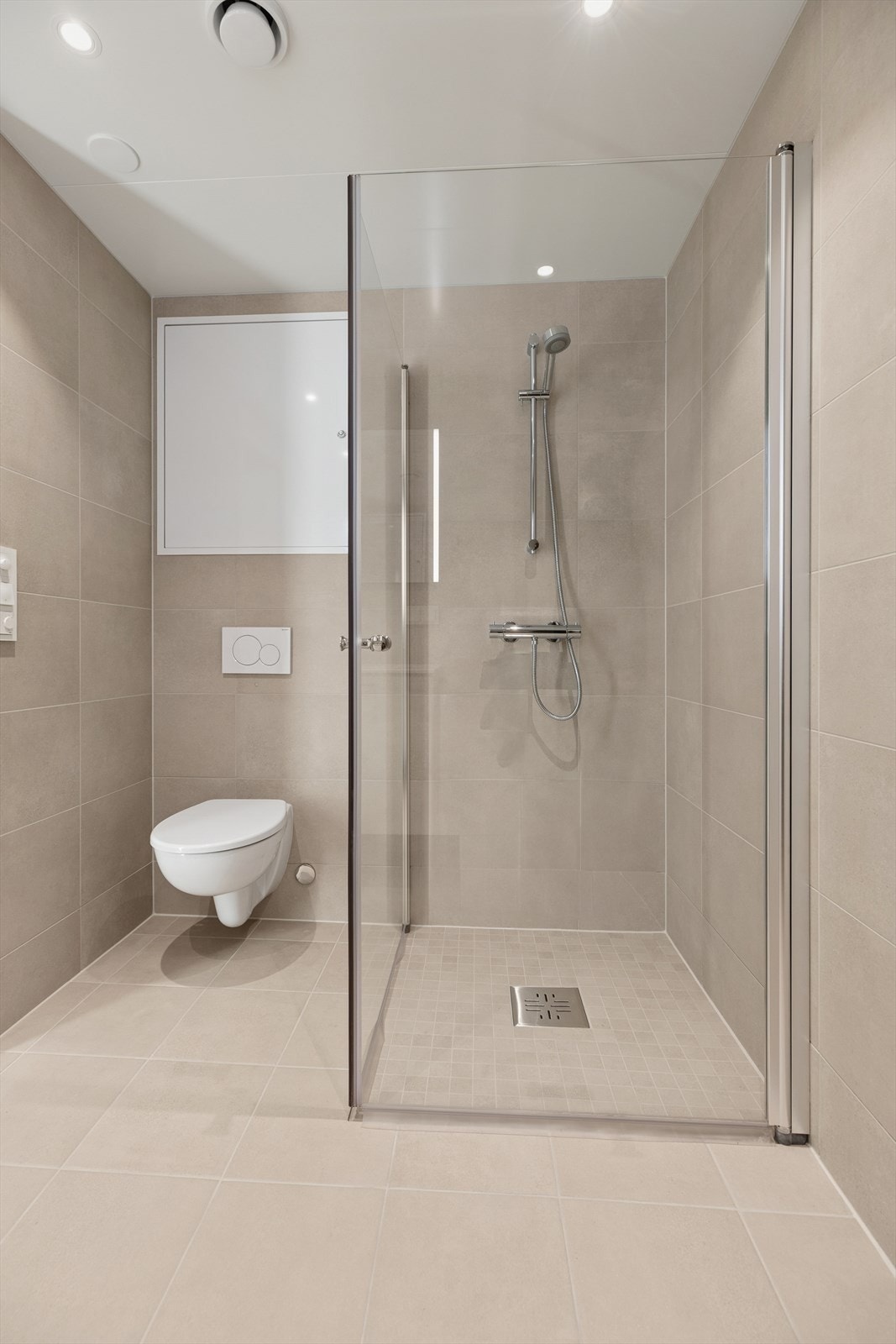 Rommet er utstyrt med dusjhjørne med svingbare skjermvegger, vegghengt klosett, hel nedfelt servant, opplegg for vaskemaskin og baderomsinnredning med servantskap og speil med integrert lys. Galleribilde