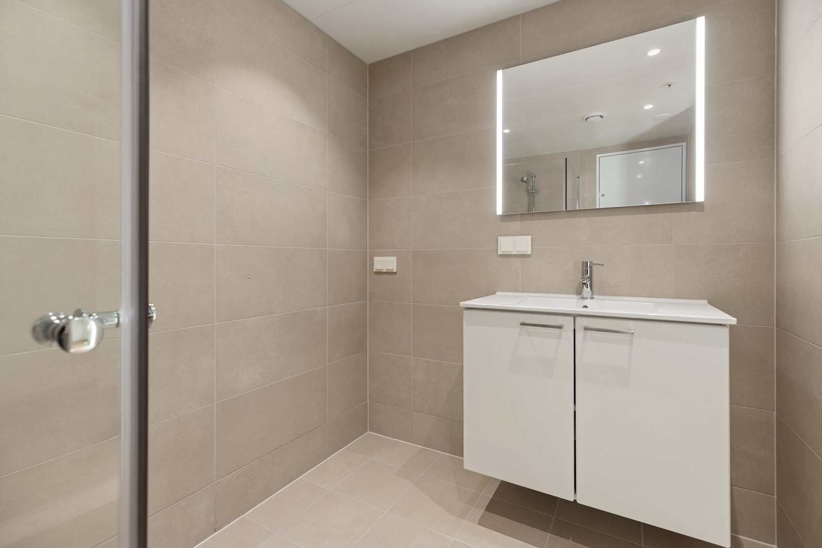 Bad 1: Kombinert bad, wc og vaskerom med adkomst fra entré/gang. Flislagte overflater, vannbåren gulvvarme og integrert belysning i himling. Våtrommet har mekanisk avtrekk til ventil i himling og tilluft via spalte under dør. Galleribilde