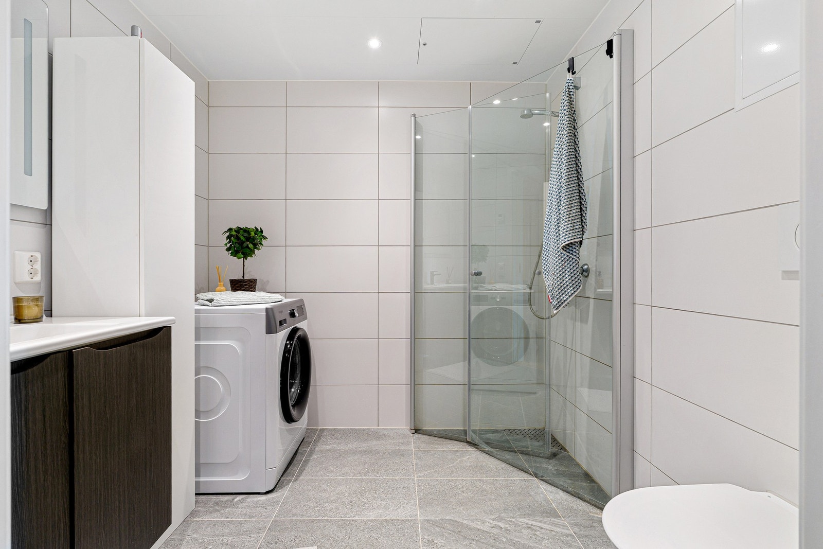 Lyst og stilfullt baderom med lekre 60x30 fliser og vannbåren varme. Veggene er flislagte, og i himlingen er det plater med innfelte spotter. Galleribilde