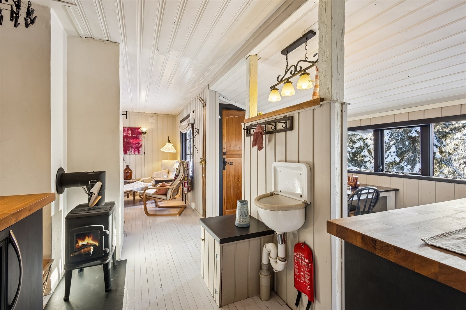 I tillegg til peisen, gir en eldre vedovn ekstra varme mellom stue og kjøkken. Galleribilde