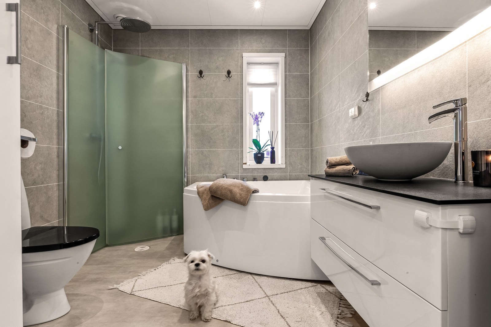 Stilrent baderom utstyrt med dusjnisje, badekar, dobbel servant og gulvstående toalett Galleribilde