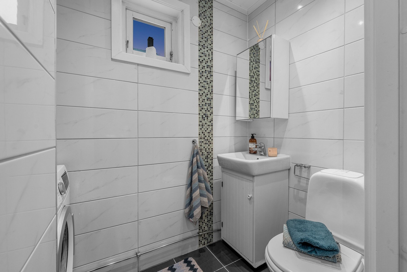 Praktisk toalettrom med flislagte overflater og effektiv utnyttelse av plassen. Galleribilde