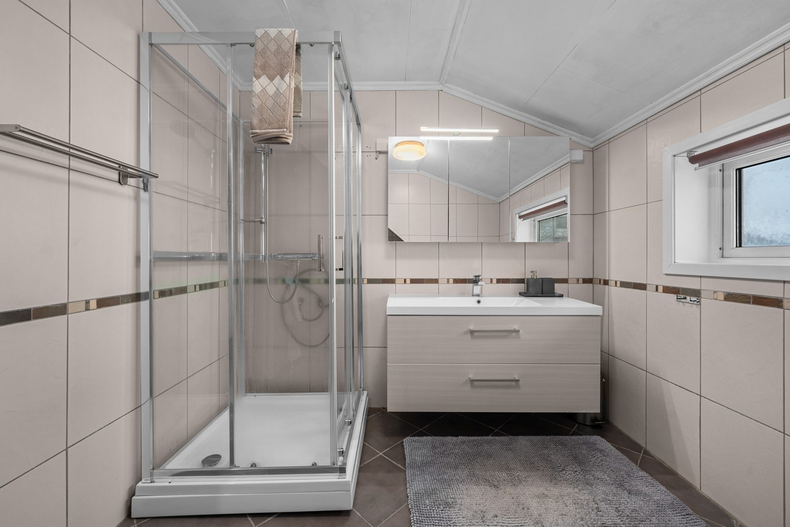 Badet har romslig dusjløsning og servantinnredning med god oppbevaringsplass. Galleribilde