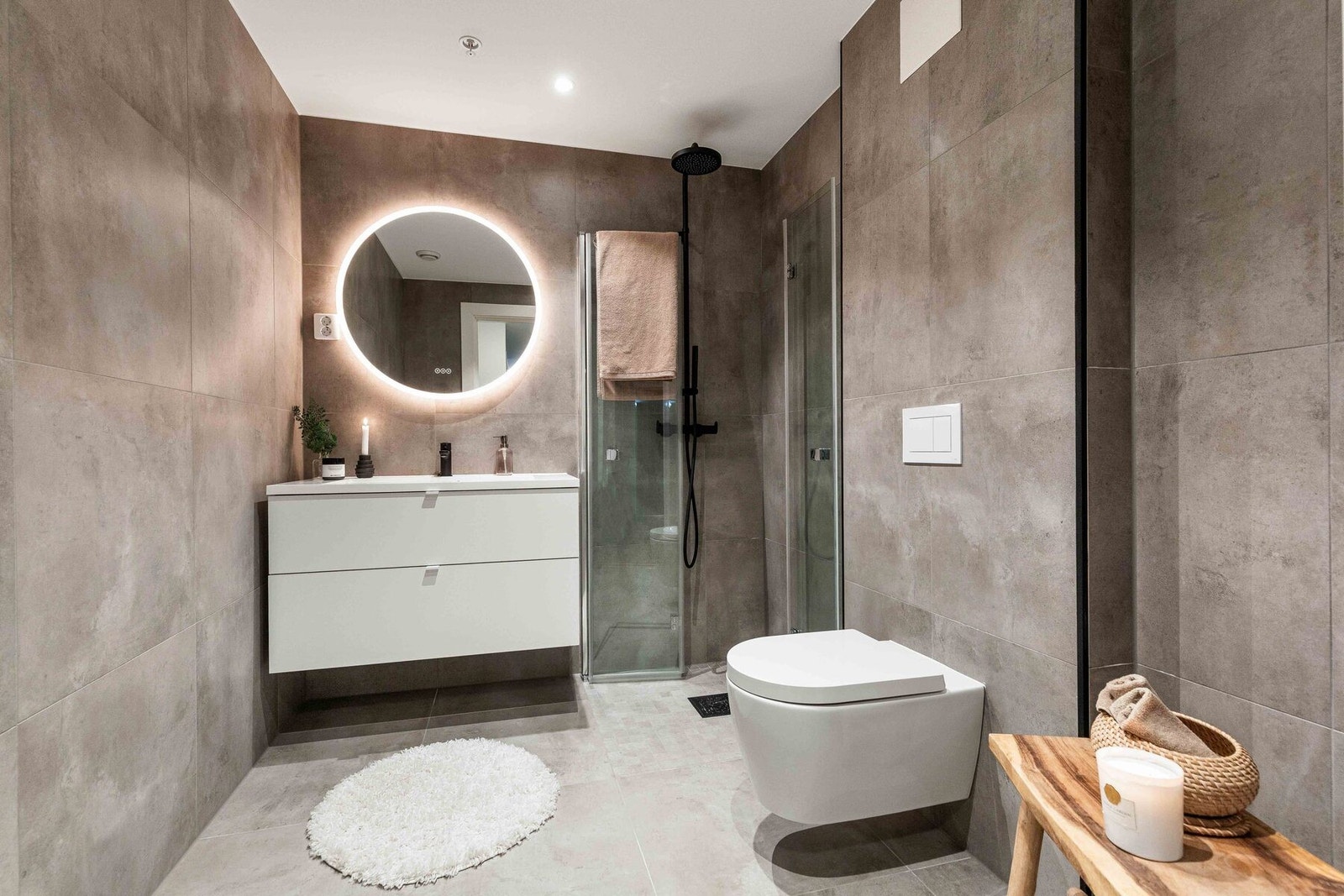 Lekkert, flislagt baderom med moderne innredning, regndusj og et stilrent speil med integrert belysning Galleribilde