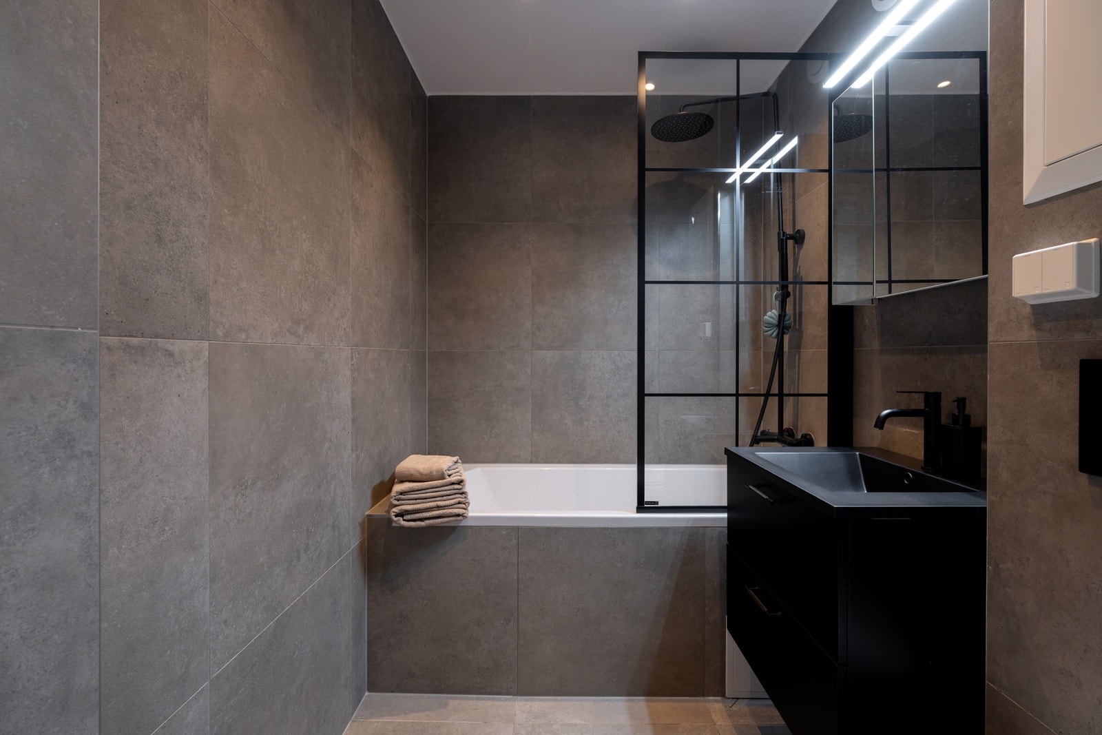 I tillegg finner du badekar med regnfallsdusj samt vegghengt toalett. De stilrene, sorte detaljene gir rommet et eksklusivt preg. Galleribilde