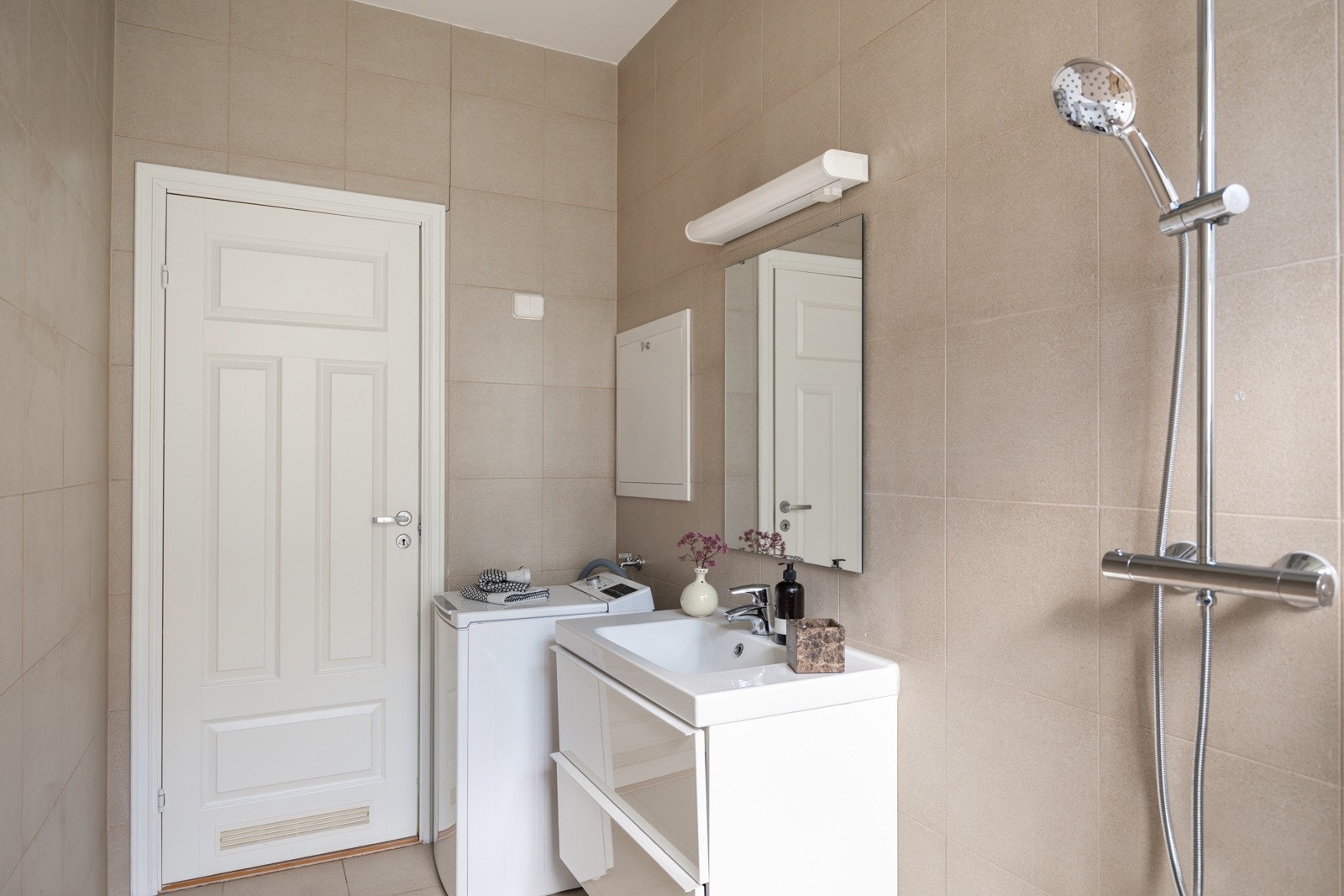 I hjørnet er det plass og opplegg for vaskemaskin. Baderommet har delikate fliser på gulv og vegger, elektriske varmekabler, downlights i himlingen og mekanisk avtrekk (Villavent). Galleribilde