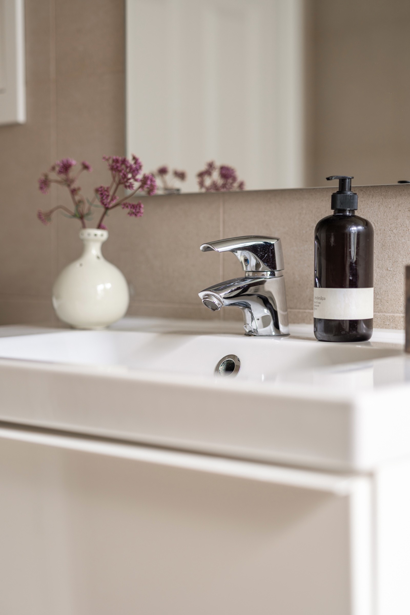 Moderne baderomsinnredning med skuffer og heldekkende servant, speil med belysning over. Galleribilde