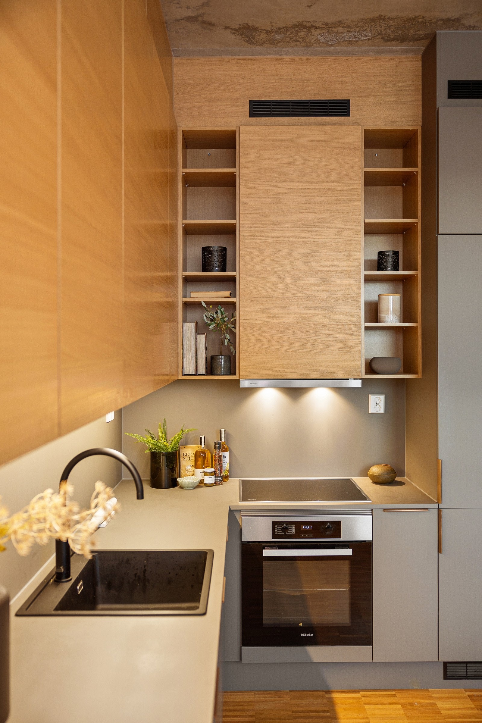 Overskapene i tre som strekker seg helt til taket bryter godt med resten av kjøkkenet, og setter preg på oppholdsrommet. Galleribilde