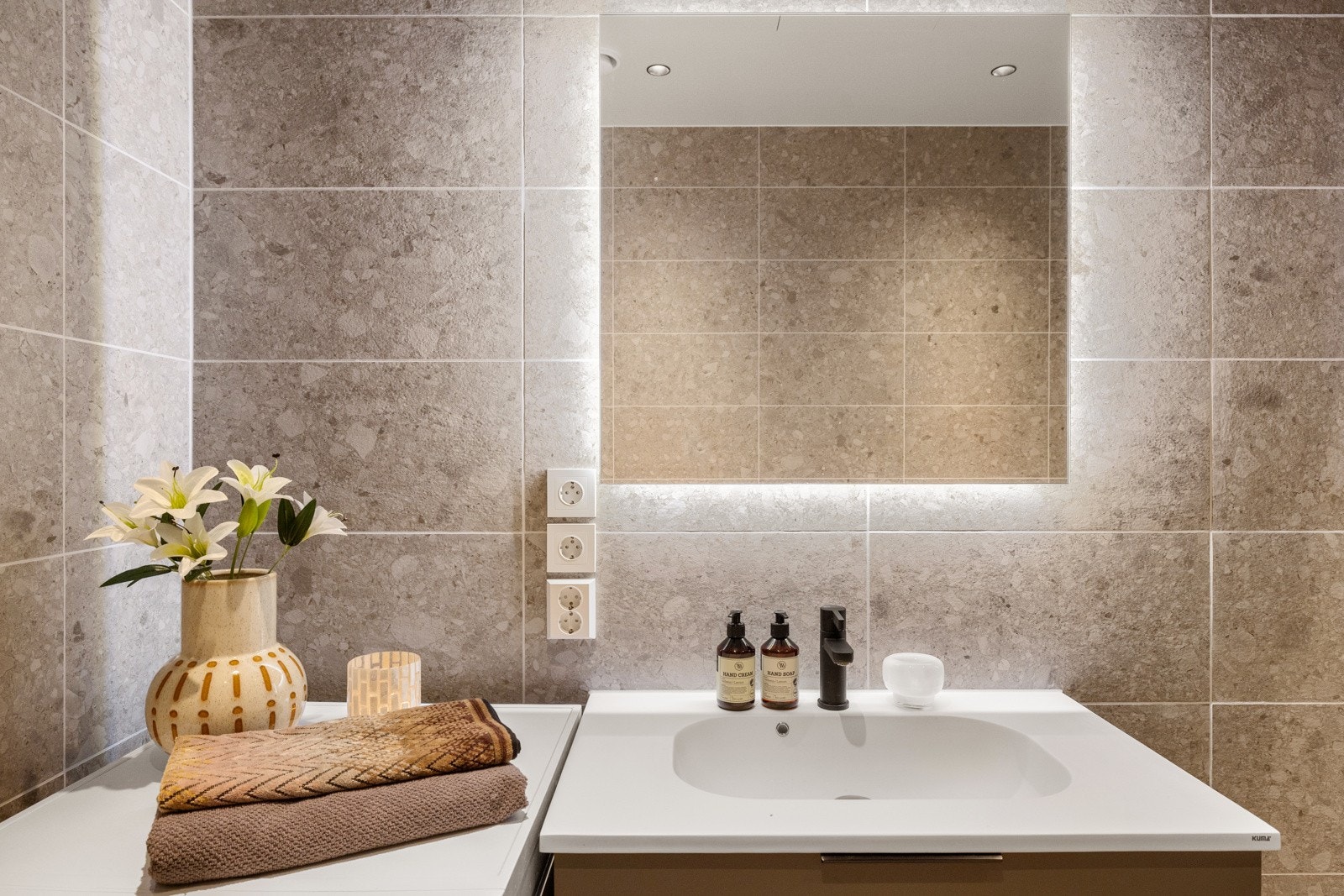 Badet inneholder vegghengt servantskap, speilskap med integrert lys, dusjhjørne med innfellbare glassdører og dusjarmatur tilkoblet hånddusj, samt vegghengt toalett med innebygget sisternekasse. Galleribilde