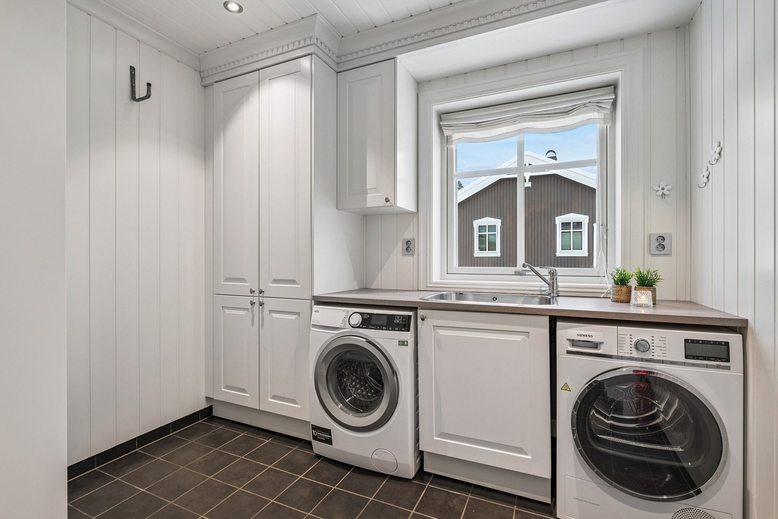 Boligen har et eget, praktisk vaskerom i første etasje med gulvvarme, utslagsvask og opplegg for vaskemaskin Galleribilde