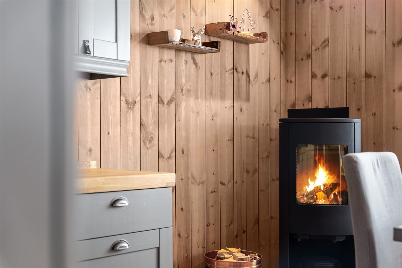 I hjørnet av rommet er det en moderne vedovn som både gir god varme og bidrar til ekstra hygge. Galleribilde