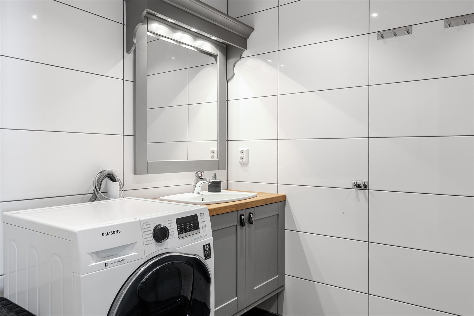 Pen baderomsinnredning med nedfelt servant, speil med belysning over. I hjørnet er det plass og opplegg for vaskemaskin, samt tørketrommel over om ønskelig. Galleribilde