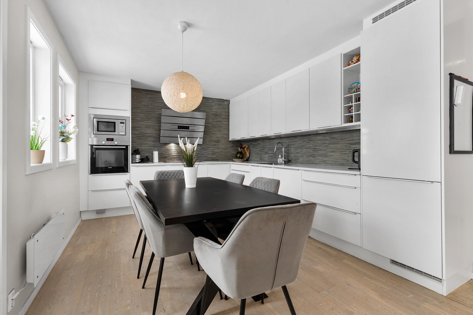 Lys kjøkkeninnredning med glatte, hvite fronter og rikelig med skap- og benkeplass. Galleribilde