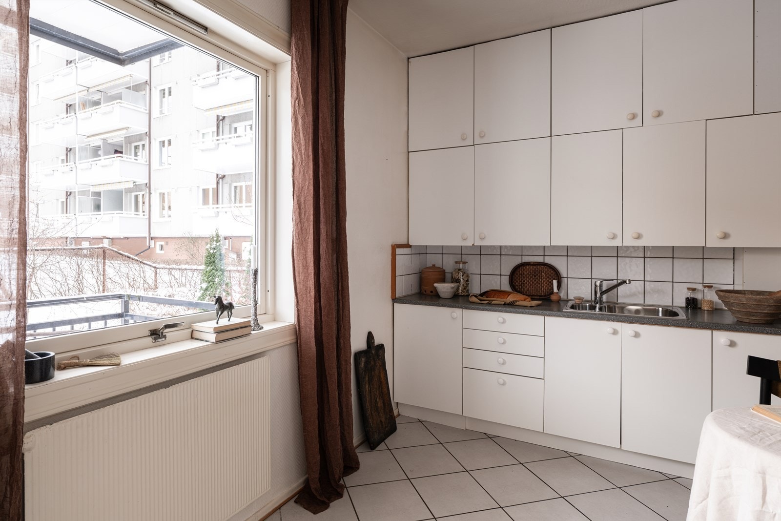 Plassen er godt utnyttet med rikelig skap- og benkeplass, og innredningen består av nøytrale, hvite fronter, fliser på bakvegg og laminert benkeplate Galleribilde