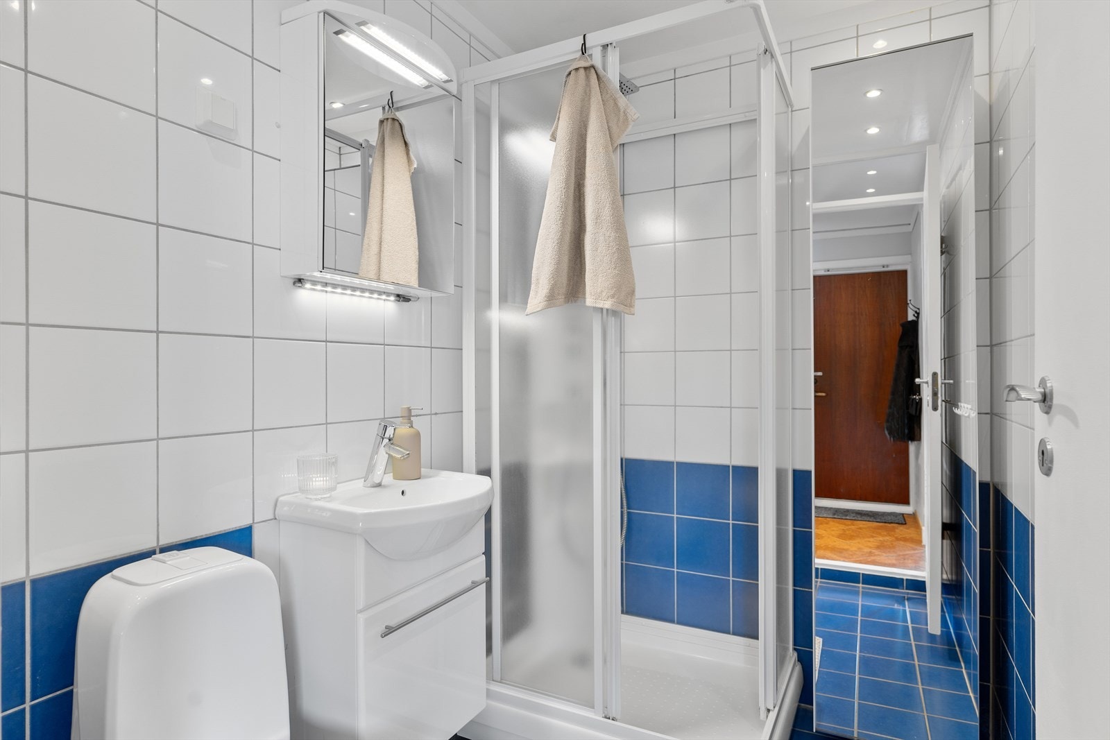 Baderommet er innredet med toalett, dusjkabinett, servant i en lys innredning. Speilskap og høyskap med speilfront. Galleribilde