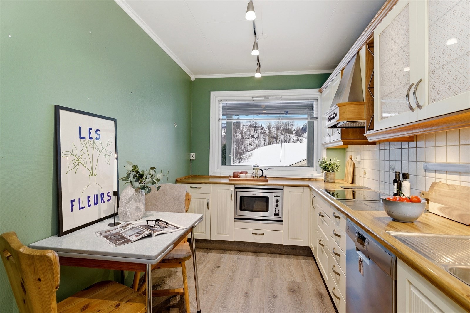 Detaljer som overskap med glass og lys, samt flislagt sprutsone, kompletterer kjøkkenet. Galleribilde