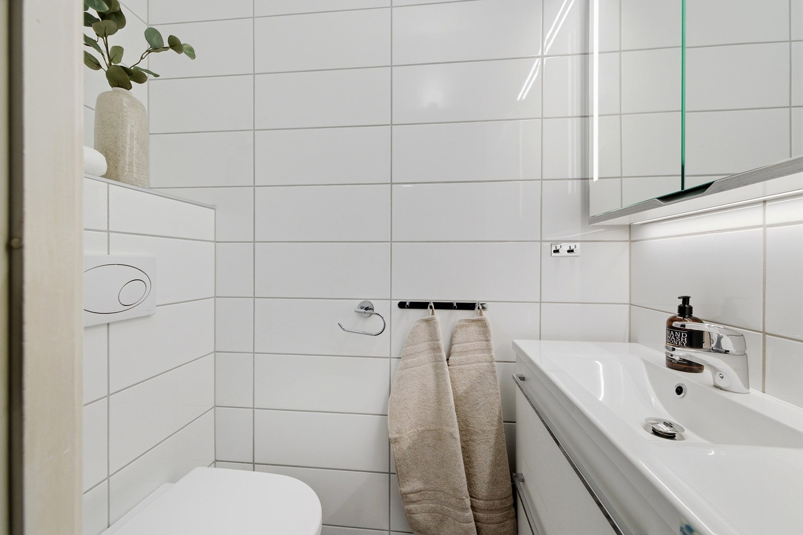 Rommet har keramiske fliser på gulv og vegger, og servantskap med servant. Galleribilde