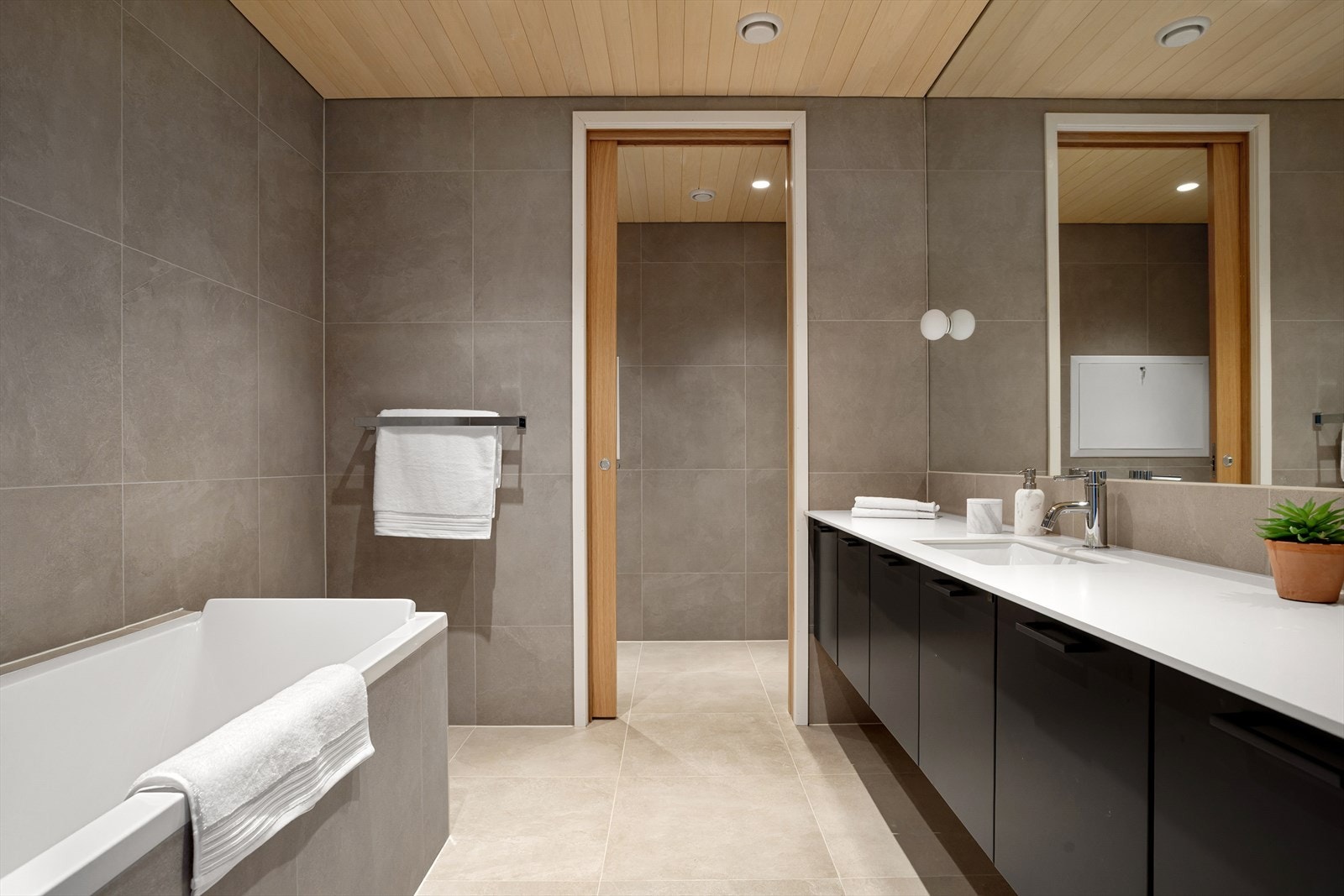 Romslig og delikat hovedbad med direkte adkomst fra hovedsoverommet. Skyvedør inn til toalettet. Galleribilde