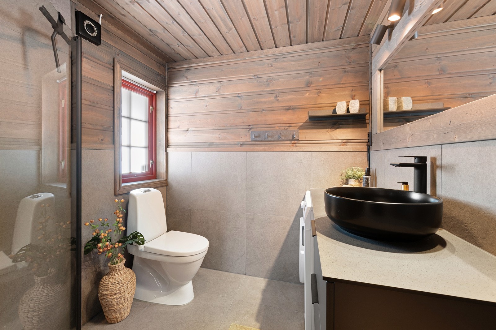 Badet er utstyrt med dusjhjørne, wc, opplegg for vaskemaskin og moderne servantinnredning Galleribilde