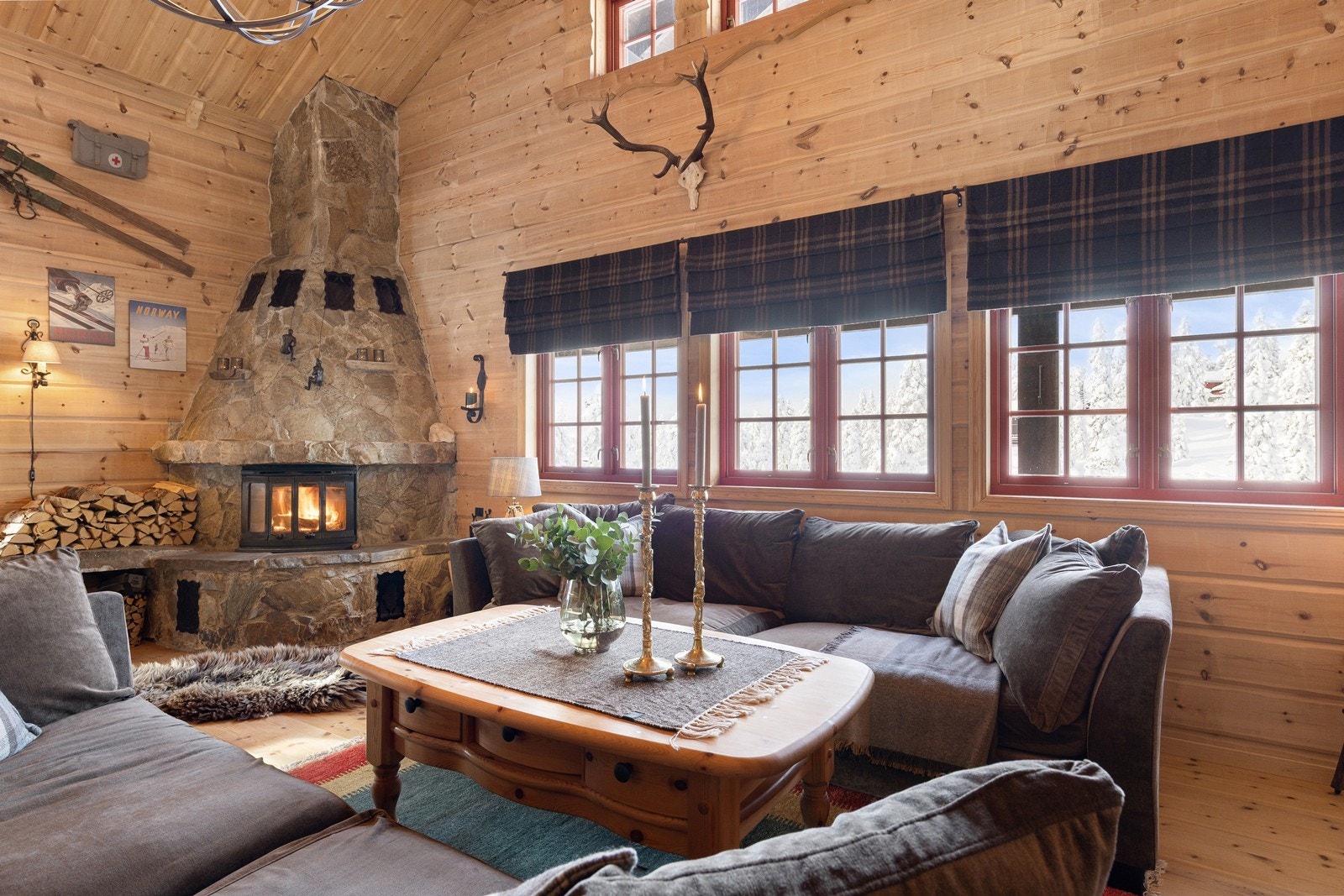 Den flotte peisen i naturstein blir et naturlig midtpunkt og skaper en varm og autentisk hyttestemning. De brede vinduene slipper inn rikelig med dagslys og gir nydelig utsyn mot vinterlandskapet utenfor Galleribilde
