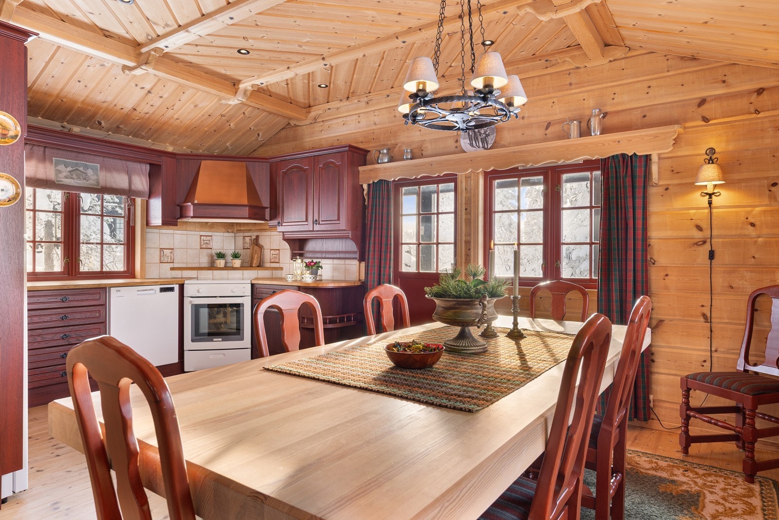 Romslig kjøkken- og spiseplass med gjennomført hyttestil og varme naturmaterialer Galleribilde