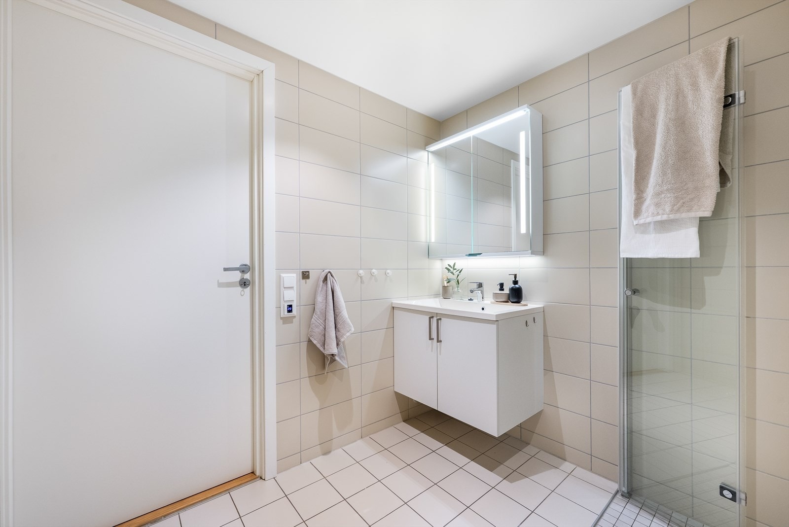 Badet er utstyrt med vegghengt toalett, dusj og en baderomsinnredning med heldekkende servant og speilskap. Det er i tillegg opplegg for vaskemaskin. Galleribilde