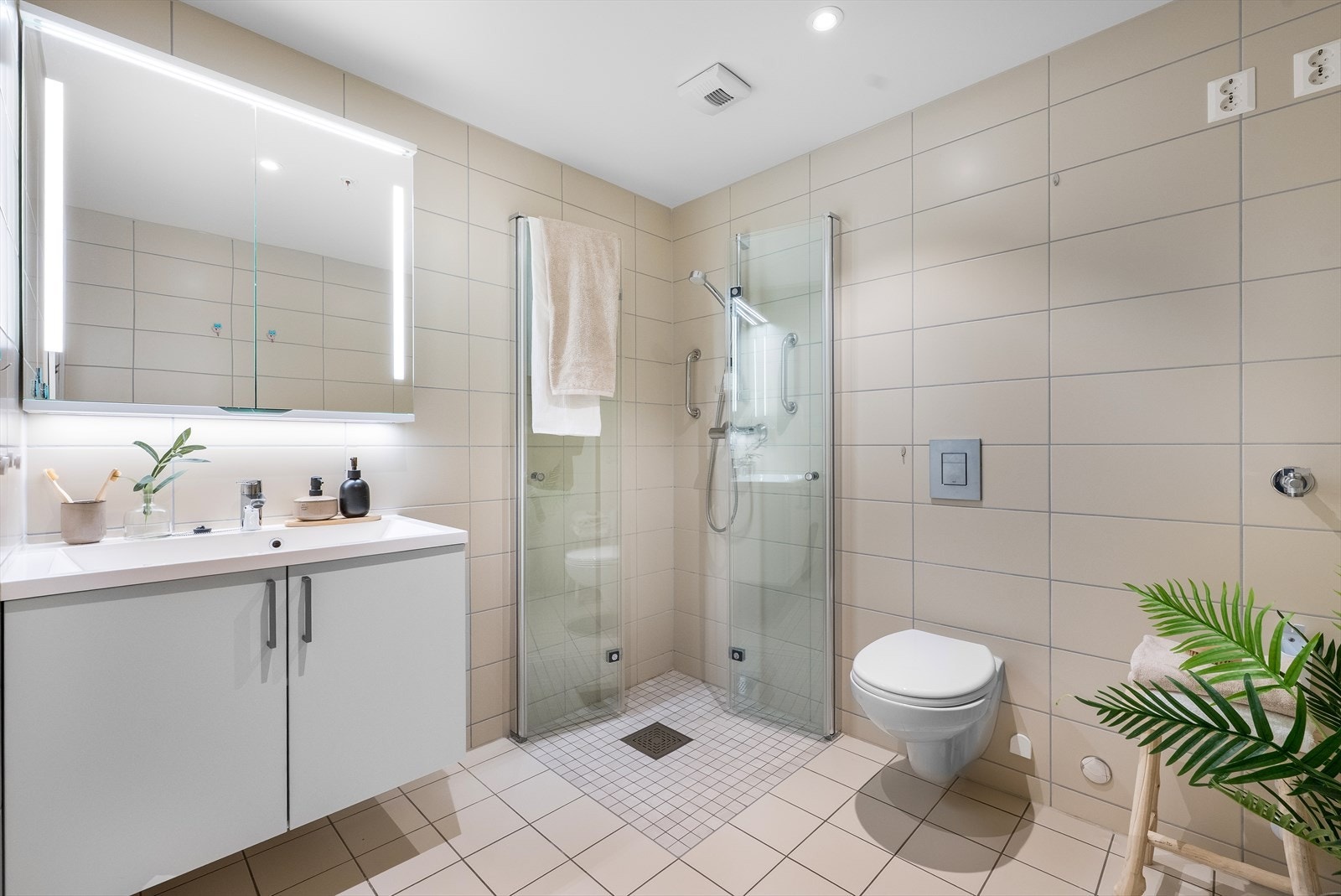 Leilighetens bad er romslig og innbydende med flislagte overflater, downlights i himlingen og elektriske varmekabler i gulvet. Galleribilde