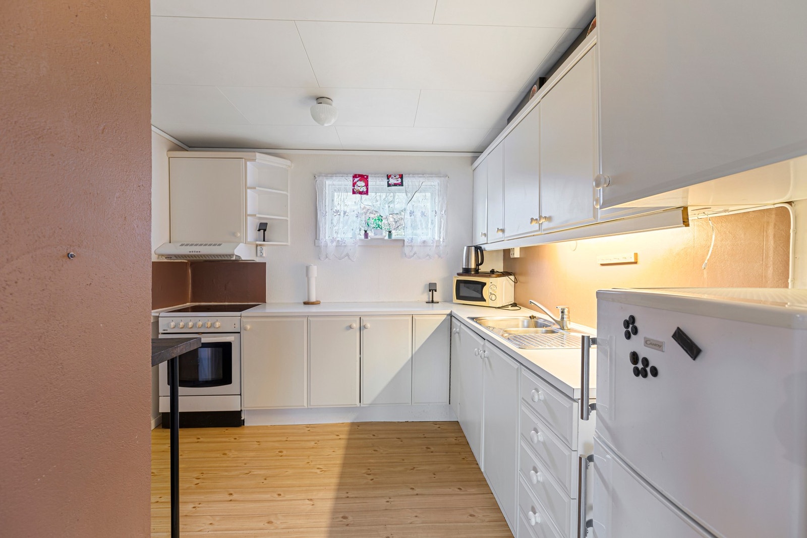 Kjøkkenet i leiligheten har enkel innredning med hvite fronter. Innredningen er utstyrt med laminat benkeplate, servant og ventilator. Galleribilde