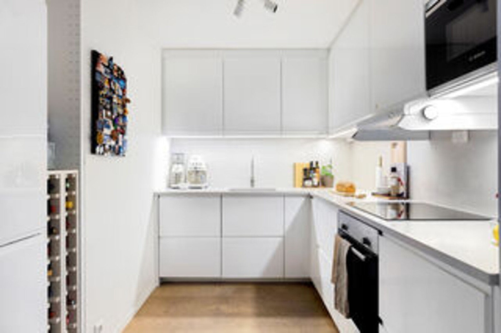 Benkeplate av stein med nedsenket oppvaskkum og ett-greps armatur.
Induksjonstopp og integrert komfyr, oppvaskmaskin og kjøleskap med fryser. Galleribilde