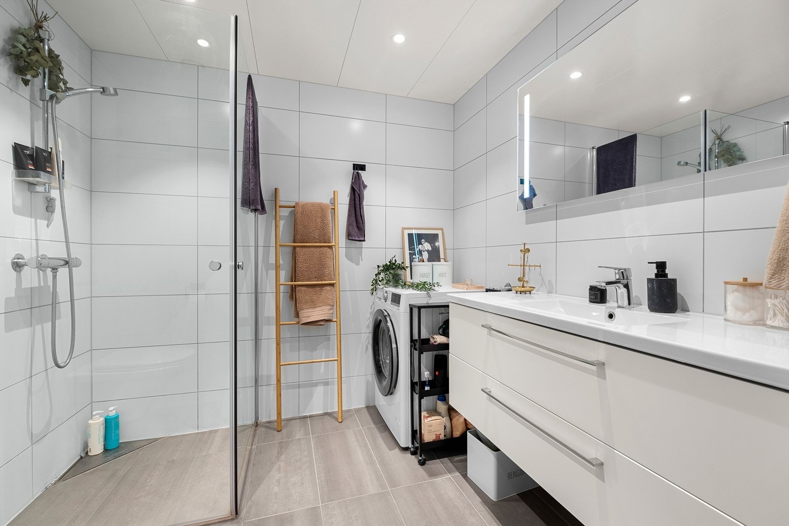 Pent flislagt baderom på ca 4,5m². Her får du flott servant med underskap, dusjhjørne, vegghengt WC og opplegg for vaskemaskin Galleribilde