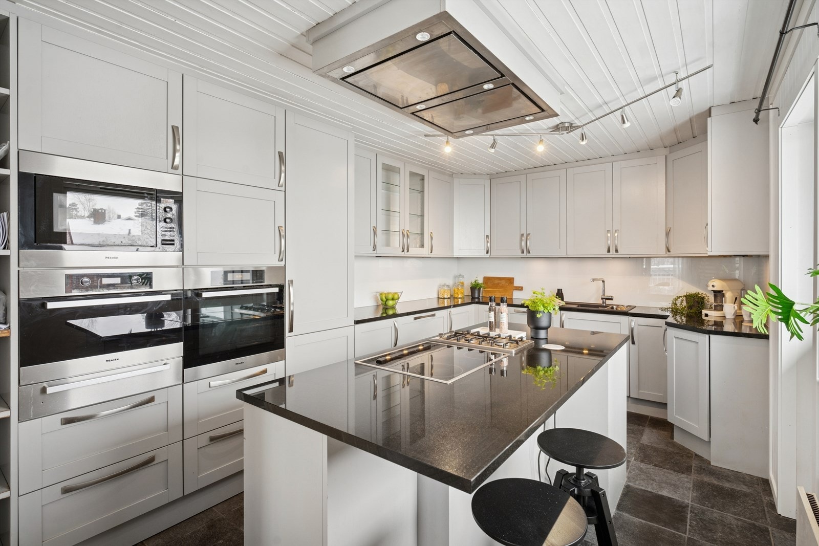 Innredningen har profilerte fronter, med enkelte glassfronter i overskapene, og komplementeres av en praktisk kjøkkenøy i samme stil. Galleribilde