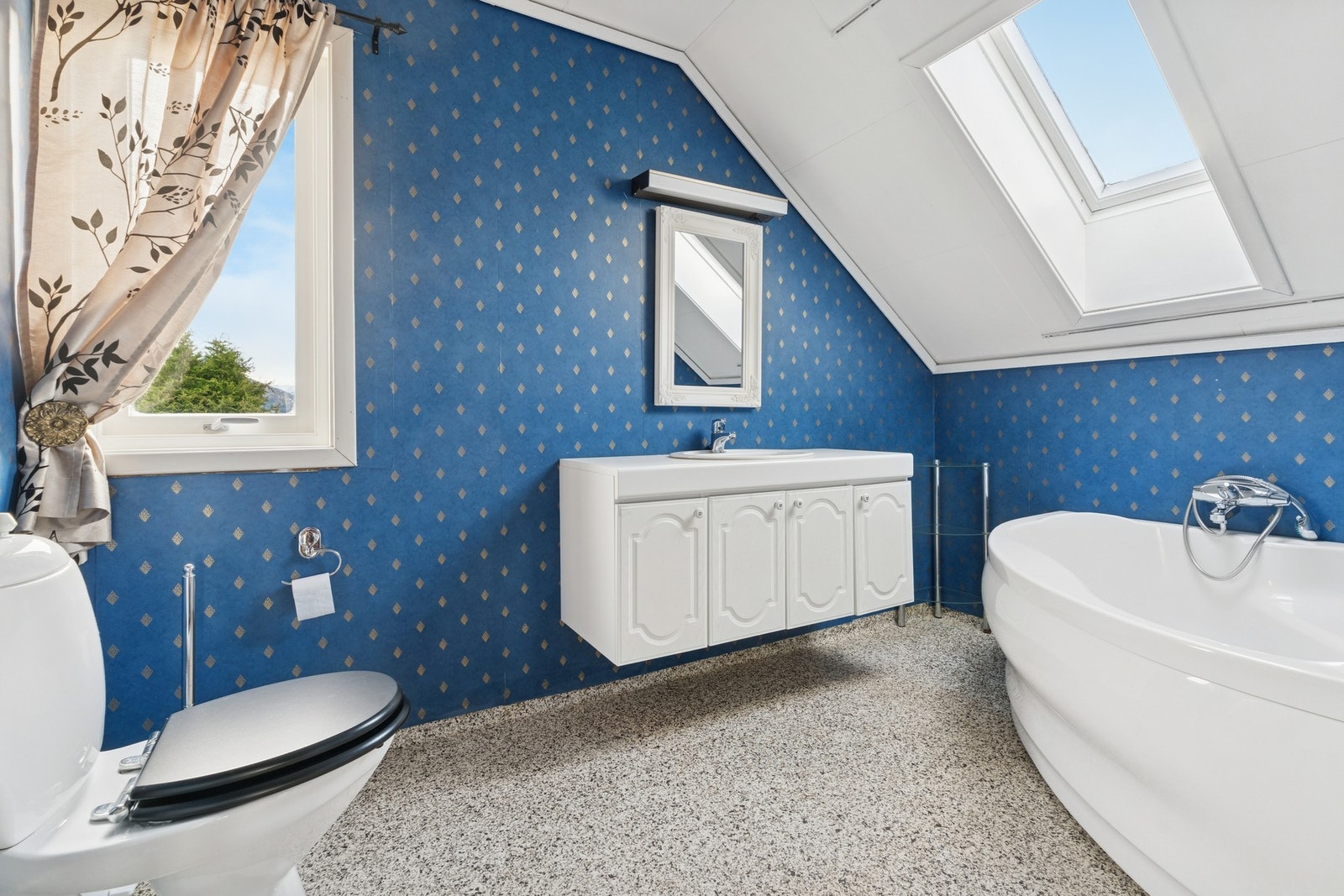 Baderom med badekar, toalett og servant. Galleribilde