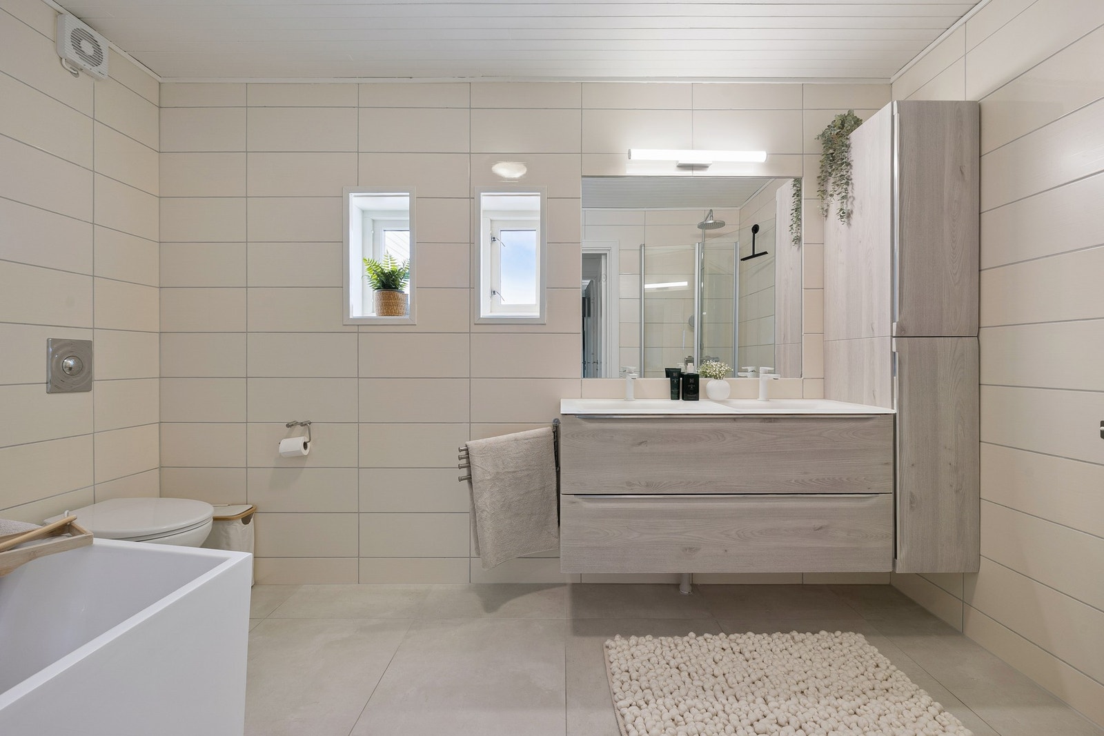 Badet er innredet med toalett, badekar, dusjhjørne og en dobbeltservant med god lagringsplass, Galleribilde