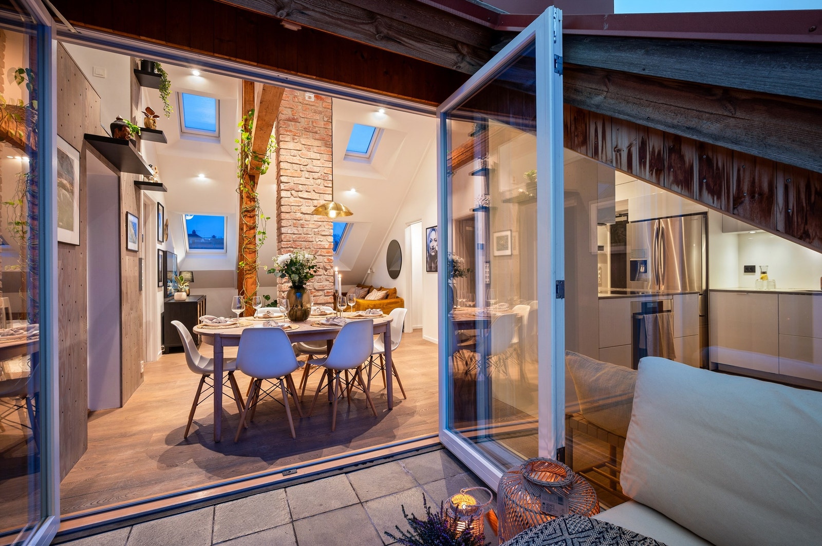 De brede dørene visker ut skillet mellom inne- og uterom på varme dager. For økt komfort er det installert elektriske varmekabler i det flislagte gulvet på terrassen. Galleribilde