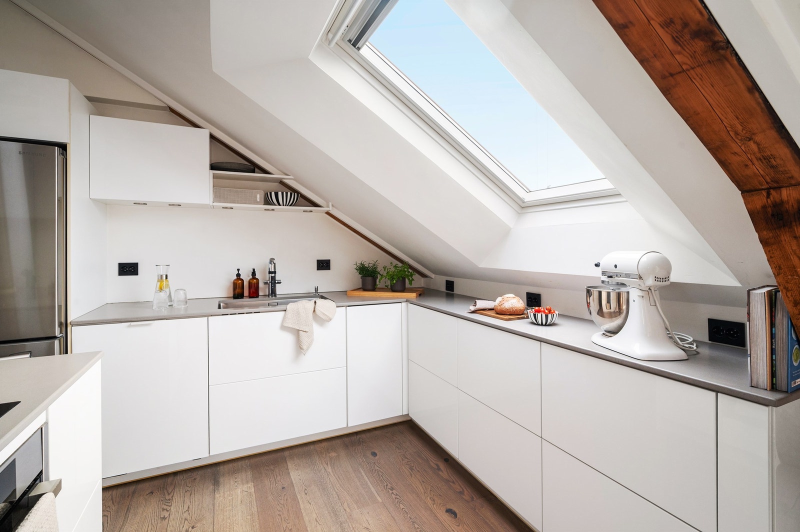 Solid benkeplate i kompositt med underlimt vaskekum gir et holdbart og stilrent uttrykk. Her får du gode arbeidsflater og smart utnyttelse av plassen under skråtaket. Galleribilde