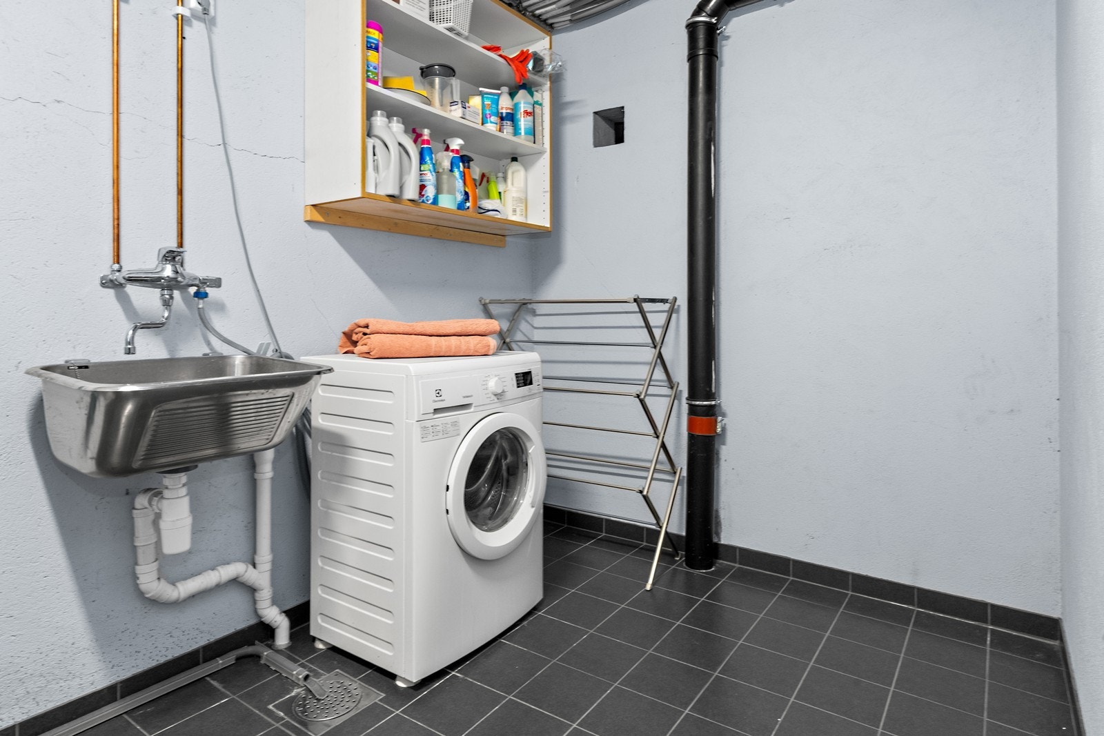 Et praktisk vaskerom med varmekabler i gulvet, utslagsvask opplegg for vaskemaskin. Galleribilde