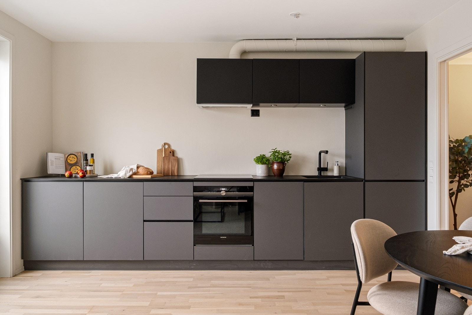 Lekkert kjøkken fra 2018 med mørke, glatte fronter og laminert benkeplate med nedfelt kum. Galleribilde