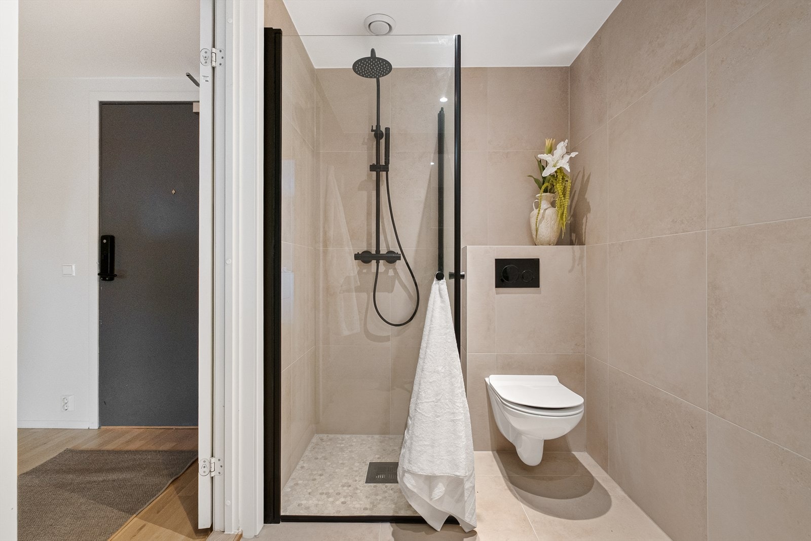 Badet er innredet med dusjsone med hånd- og regndusj, vegghengt toalett, servant med innredning, speilskap og opplegg for vaskemaskin. Galleribilde