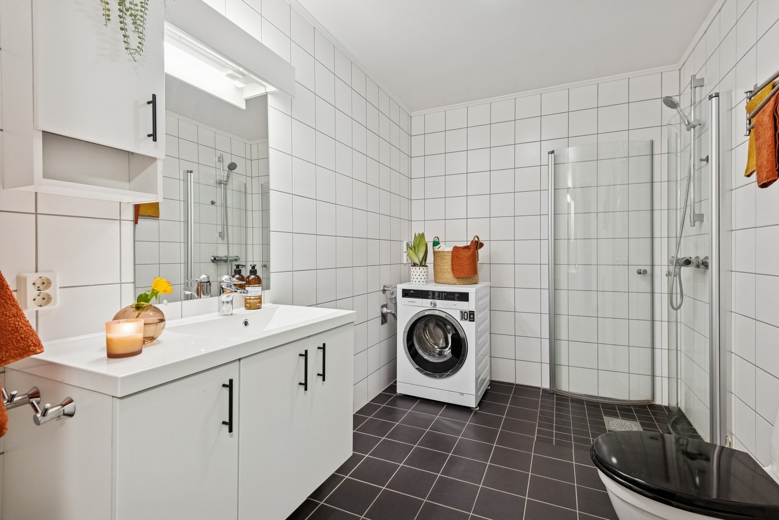 Flislagt bad med gulvvarme. Rommet er innredet med servant, dusjhjørne, toalett og opplegg for vaskemaskin. Galleribilde