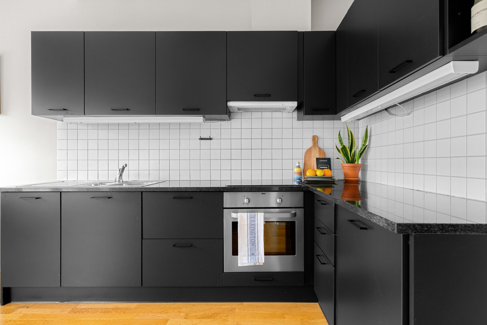 Innredningen har sorte glatte fronter og påkostet benkeplate av stein med nedfelt oppvaskkum. Praktisk med lyse fliser i benkeryggen og belysning under overskapene. Galleribilde