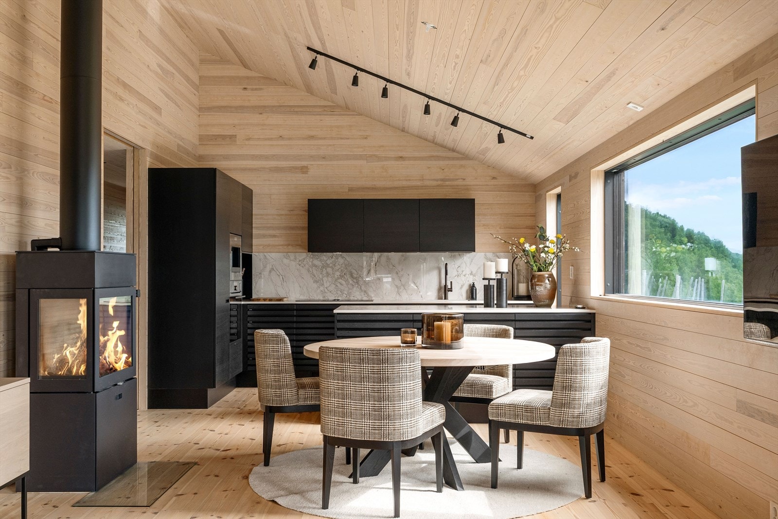 Den luftige oppholdsdelen har stue- og kjøkkenløsning med åpen himling og store glassflater Galleribilde