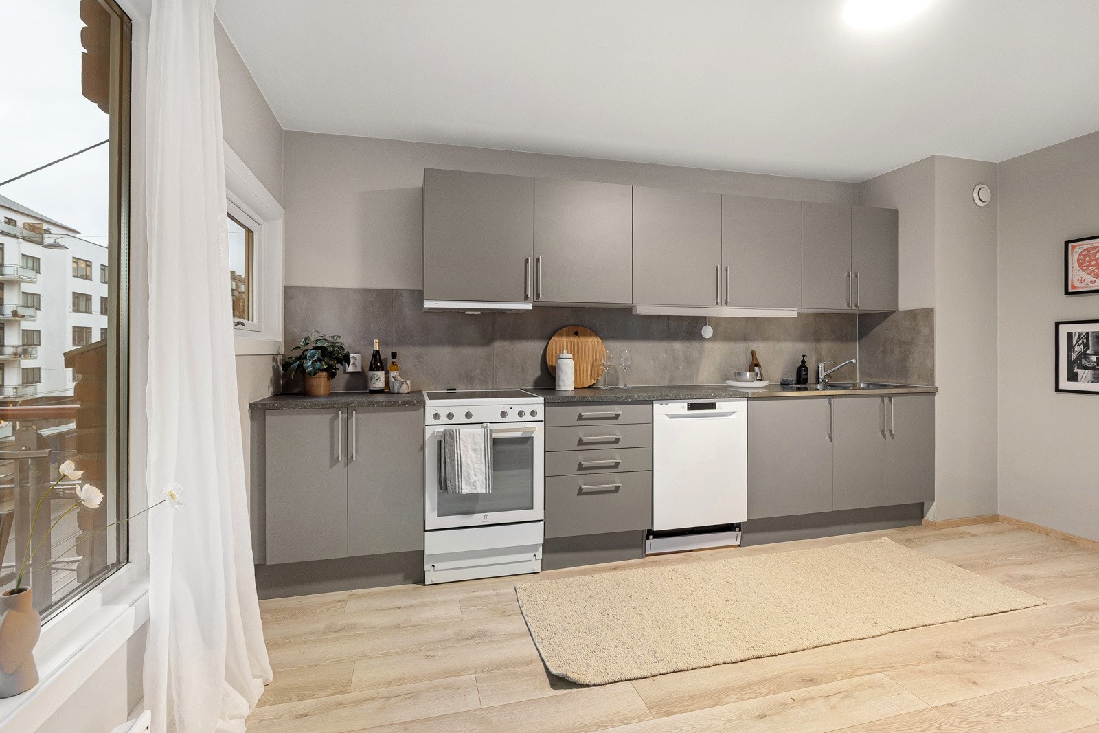 Stort og moderne Tvis-kjøkken fra 2022, med glatte fronter og laminert benkeplate med nedfelt oppvaskkum i stål. Galleribilde