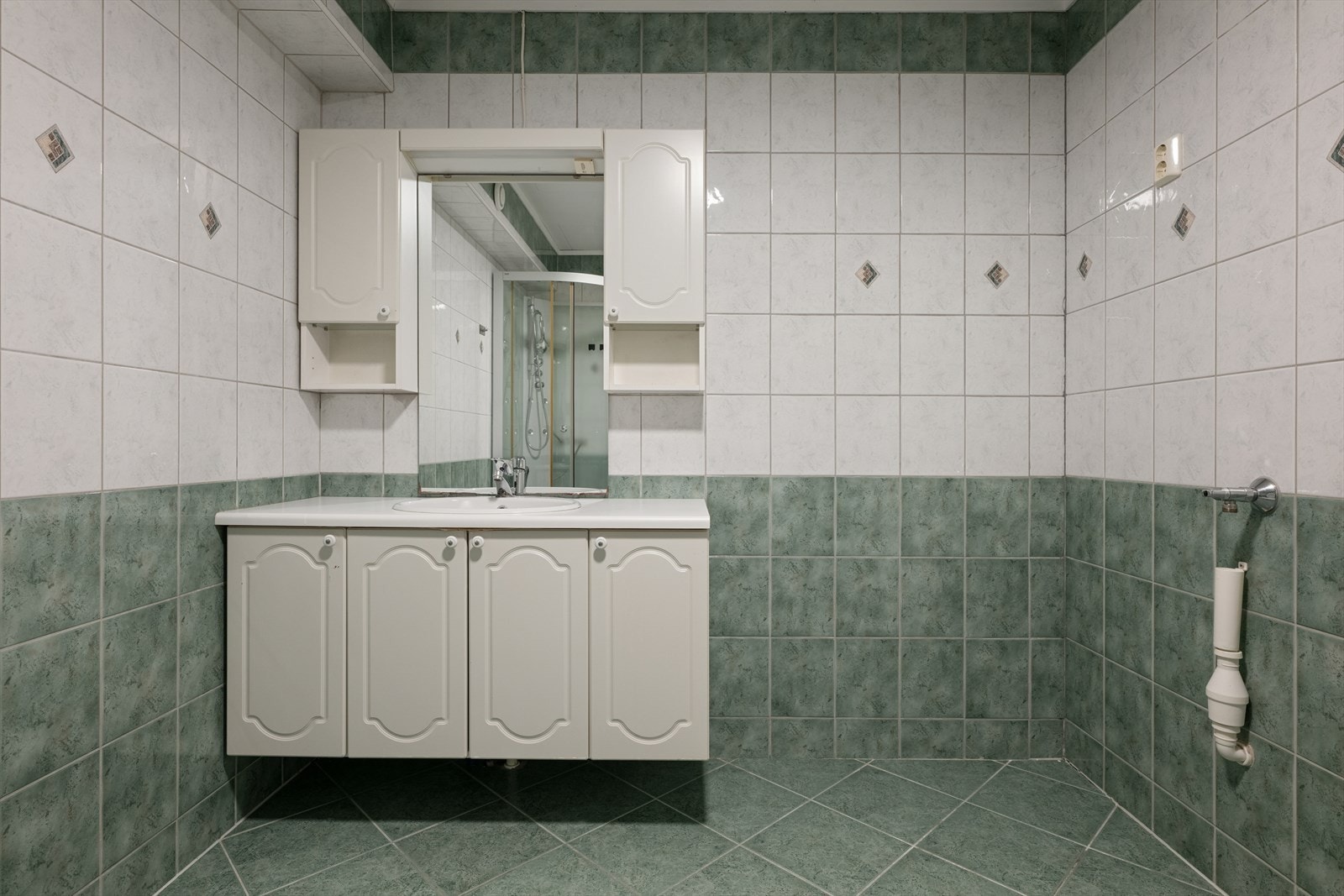 Romslig, flislagt bad med servantinnredning som gir gode oppbevaringsmuligheter. Galleribilde